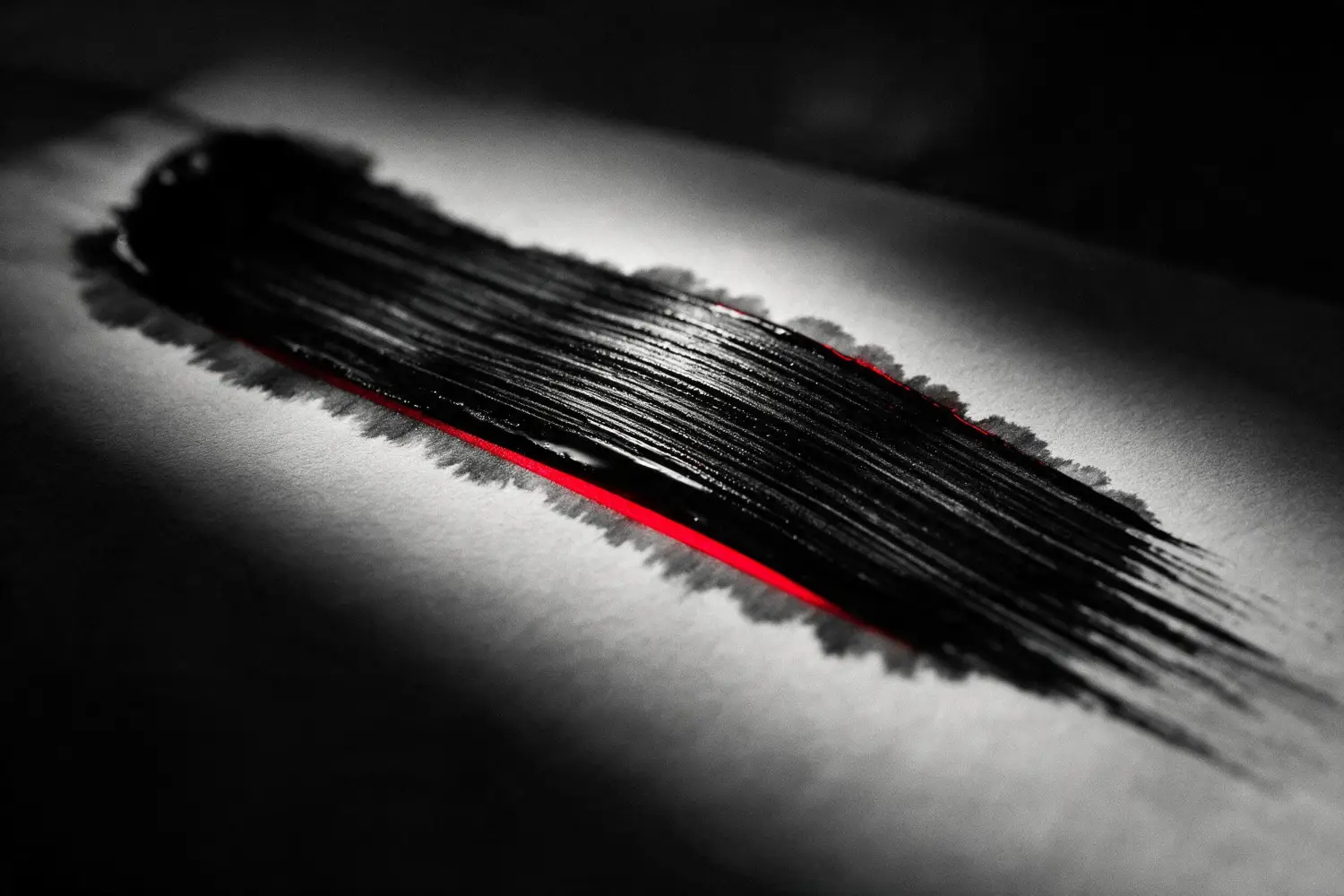 A single wide calligraphy brush stroke pulled across paper over a red guideline.