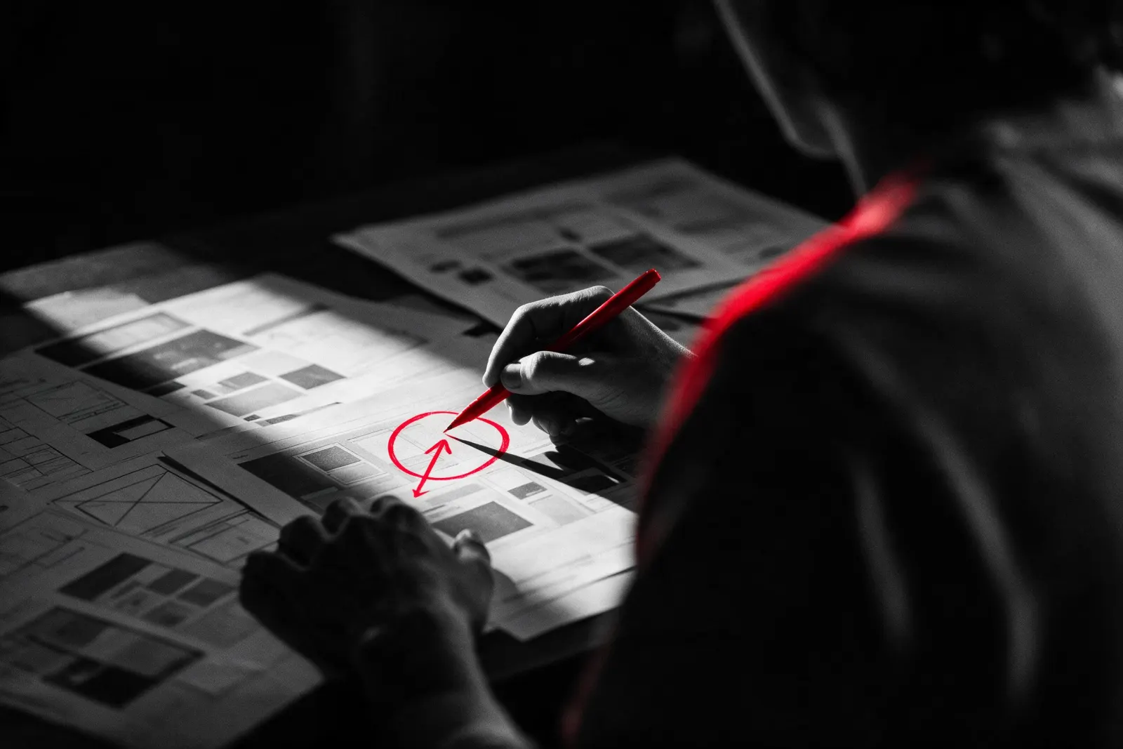A hand marking a printed layout in red pen, circling one decision.